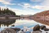 A Winter's day at Capel Curig looking along the lake of Llyn Mymbyr towards the snow covered mountains of the Snowdon Horseshoe. Beautiful reflections of the trees and hillside in the perfectly still water. North Wales